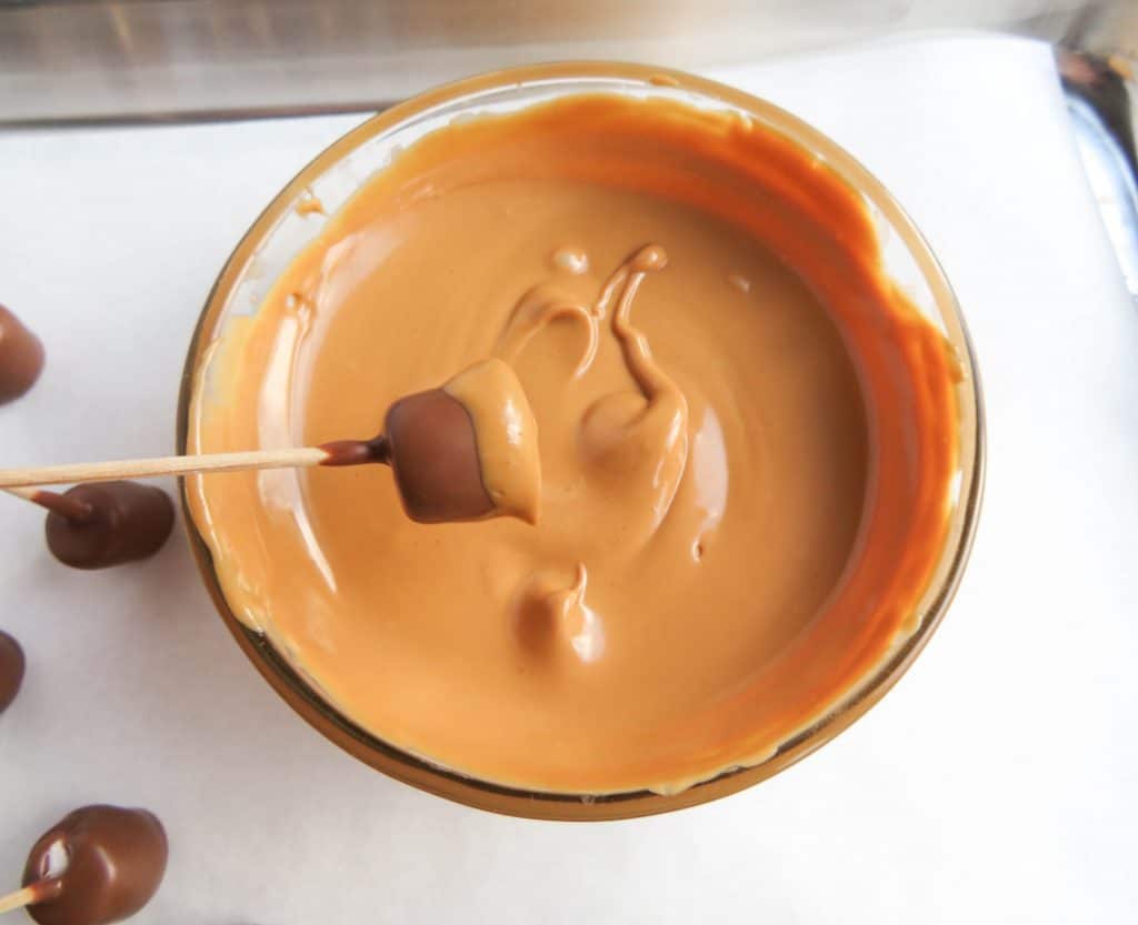 dipping salted caramel and chocolate fall treats into the caramel
