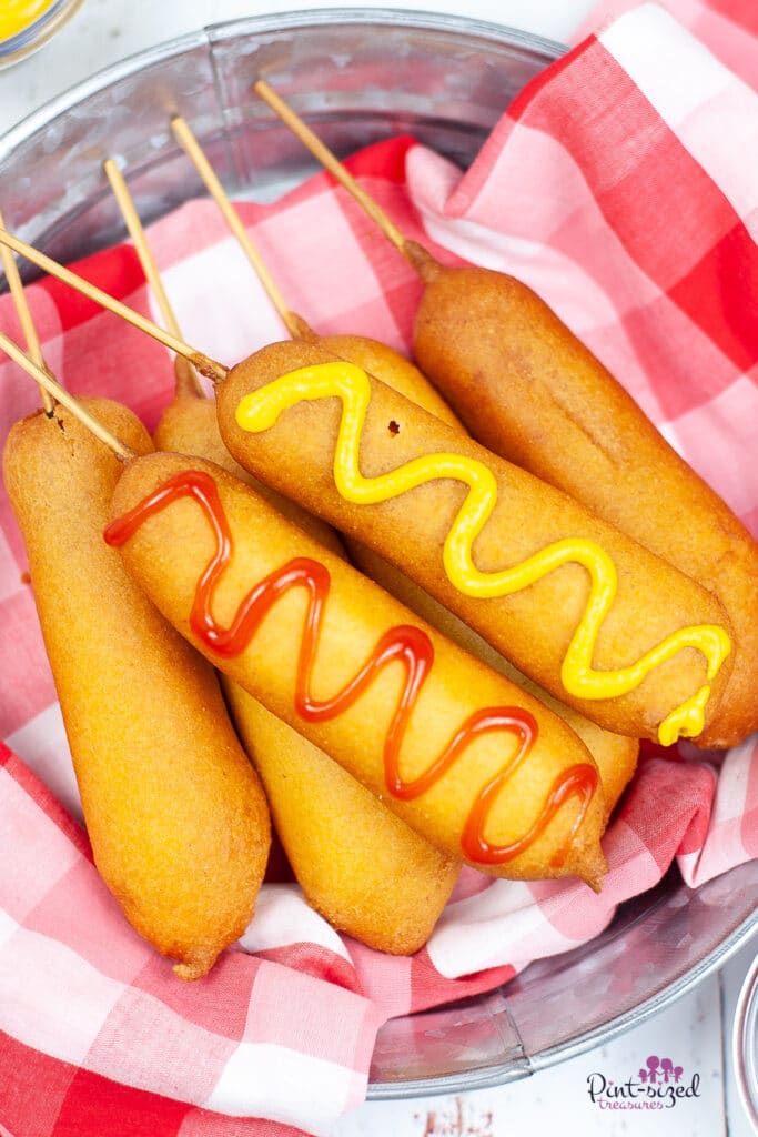homemade corn dogs covered in mustard and ketchup