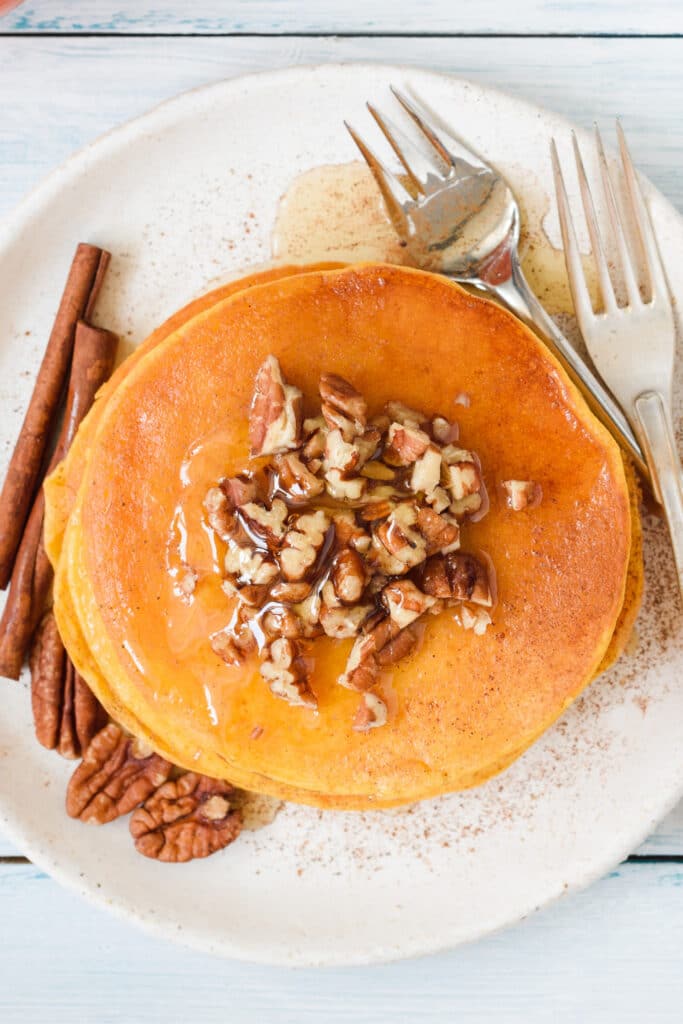 pumpkin pancakes with syrup, pecans, and cinnamon
