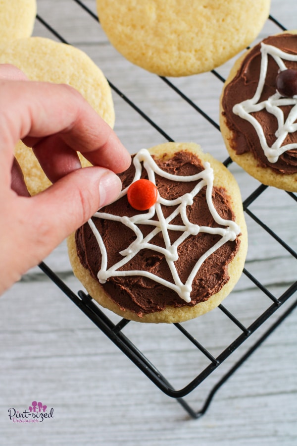 adding candy to spider web cookies