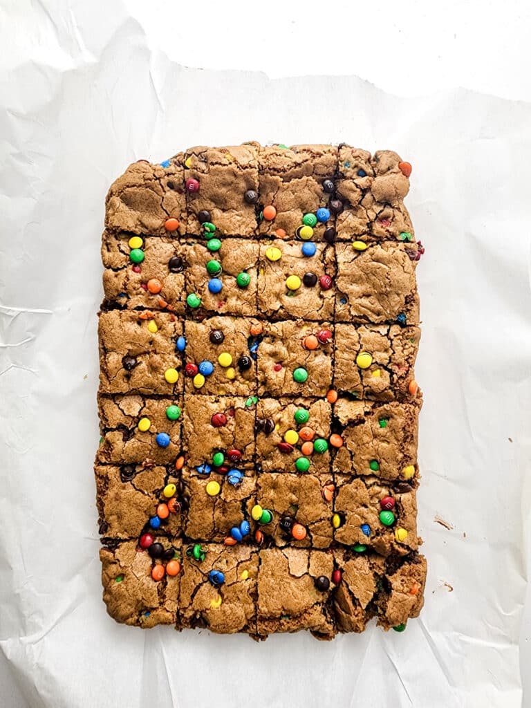 M&M cookie bars cut into squares on parchment paper