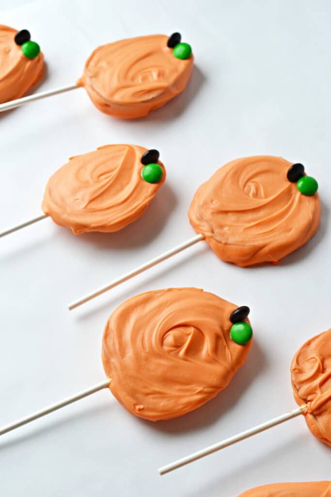 apple slices dipped in chocolate and shaped and decorated into pumpkin pops