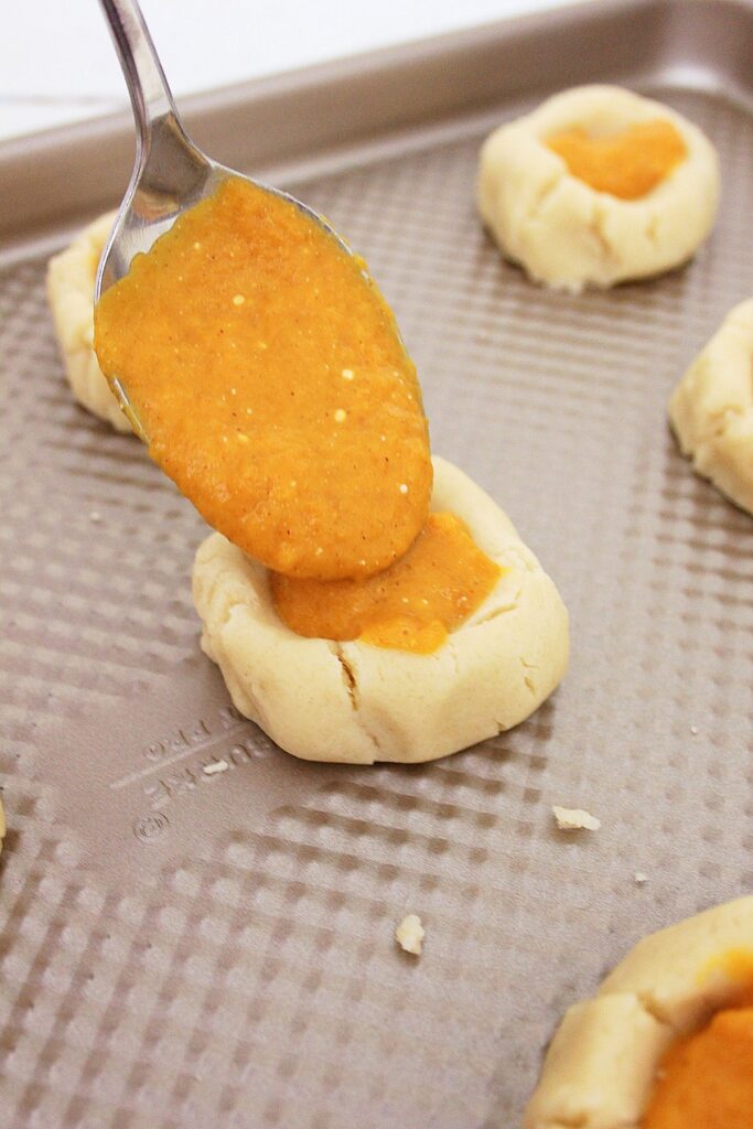 putting filling in pumpkin thumbprint cookies